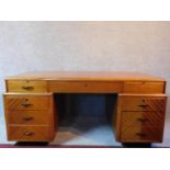 A mid 20th century Art Deco style birch partner's pedestal desk fitted with an arrangement of