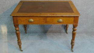 A Victorian oak leather inset two drawer writing table with frieze drawers raised on turned tapering