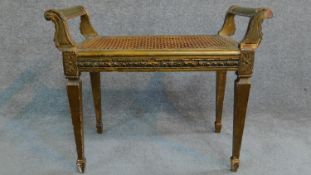 A Victorian gilt stool with caned seat on square tapering supports. H.59 W.69 D.36cm