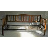 An Arts and Crafts oak day bed with heart shaped motif to cresting rail, slatted back and sides on
