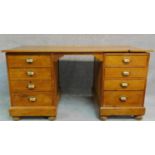 An Edwardian pitch pine pedestal desk with kneehole section flanked by drawers raised on bun feet.