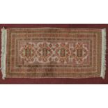 An Afghan rug with four pendant medallions on an ivory and rouge field within geometric design