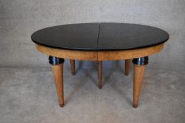 A Continental Art Deco bird's eye walnut extending D end dining table with ebonised top and two