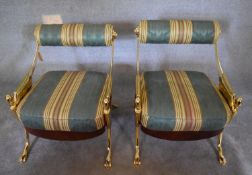 A pair of heavy brass framed salon chairs with arm supports in the form of winged spirits raised