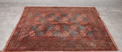 A bokhara style rug with rouge ground and geometric border. H.157 x 134cm