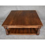 A large square country oak coffee table on turned supports united by undertier. H.47 x 122 x 122cm