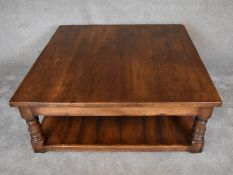 A large square country oak coffee table on turned supports united by undertier. H.47 x 122 x 122cm
