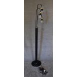 A floor standing lamp with black base and three branches each with brass light fittings,