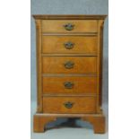 A Georgian style burr walnut bedside cabinet fitted with five short drawers, raised on bracket feet.