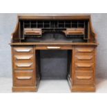 A late 19th century oak roll top desk with tambour shutter enclosing fitted interior above an