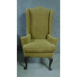 A Georgian style mahogany framed upholstered wing armchair, raised on shell carved cabriole