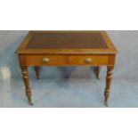 A Victorian oak leather inset two drawer writing table with frieze drawers raised on turned tapering