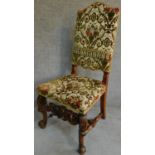 A Victorian carved oak armchair with tapestry style floral upholstery, raised on stretchered