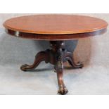 An early Victorian mahogany circular tilt top loo table raised on carved tripod base with lion paw