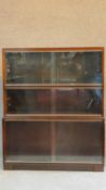 A mid 20th century mahogany two section bookcase fitted sliding glass doors on plinth base, by