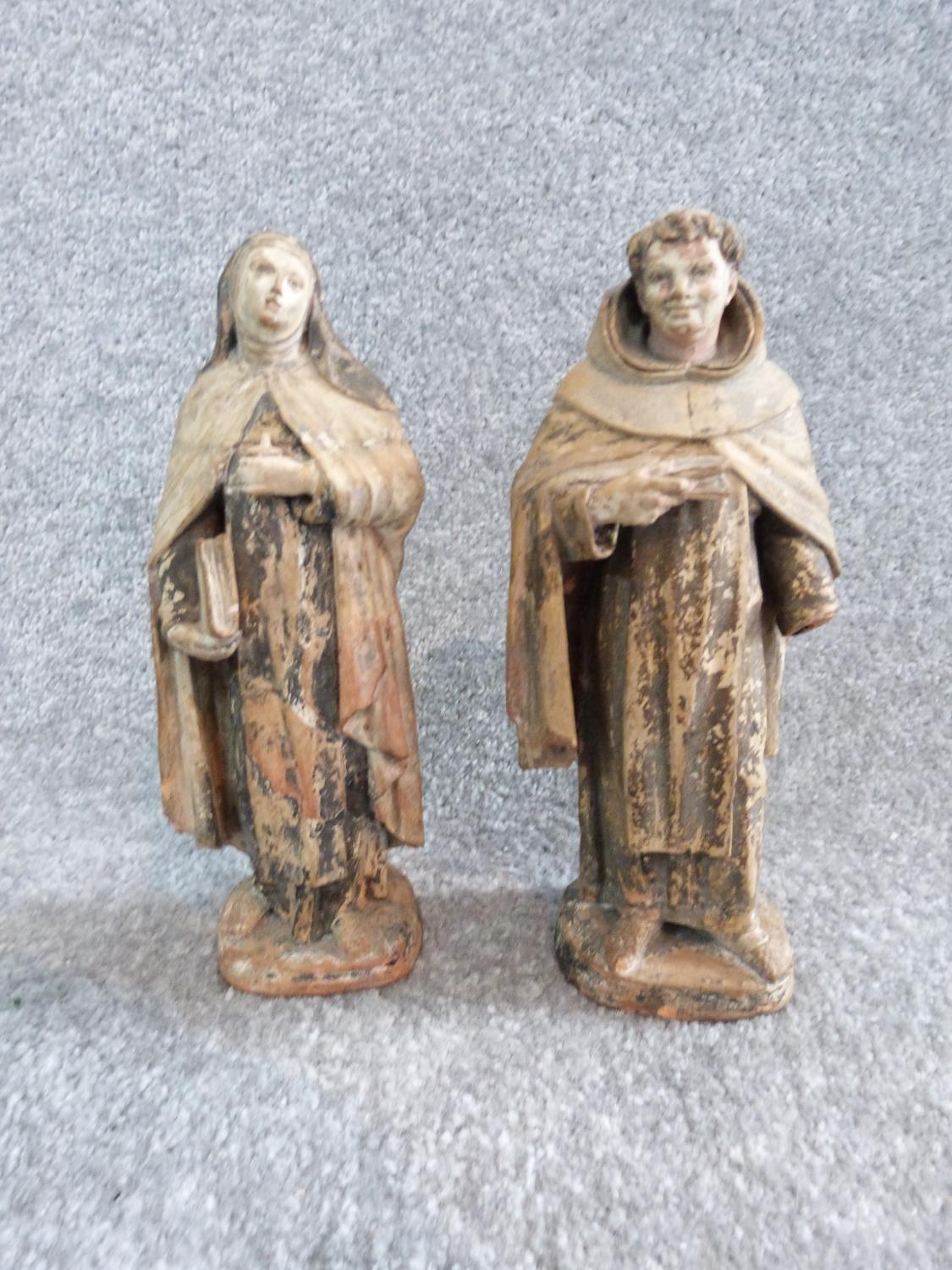 Two antique painted terracotta figures. One of a monk holding a candle and a bible and the other
