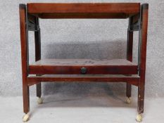 A mid 20th century mahogany metamorphic tea trolley raised on stretchered square supports with