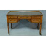 A William IV mahogany writing table with glass inset top and five frieze drawers, raised on tapering