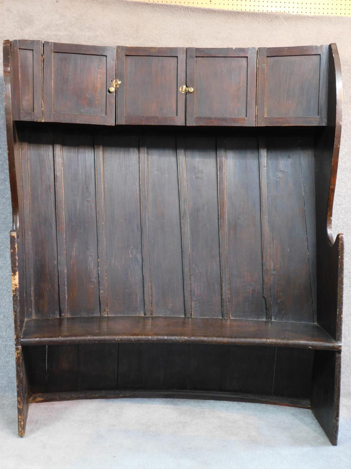 A large Georgian oak hall bench of curved outline fitted cupbooards to the upper section. W.146 D.