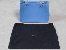 A Blue DKNY hand bag with dust cover. Silk monogrammed lining with interior zip section. Metal