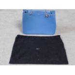 A Blue DKNY hand bag with dust cover. Silk monogrammed lining with interior zip section. Metal