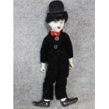 A vintage porcelain Charlie Chaplain doll. Depicting the Little Tramp with a painted porcelain head,