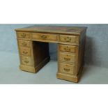 A late 19th century oak pedestal desk with leather inset top above an arrangement of nine drawers