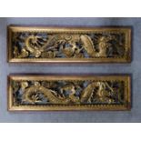 A pair of antique Chinese carved giltwood and red lacquer panels with dragon and cloud decoration.