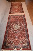 A pair of Keshan rugs with central floral medallions on a rouge field with multi stylised floral