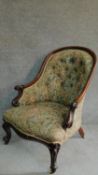 A Victorian mahogany framed floral upholstered buttoned back armchair raised on carved cabriole