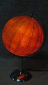 A vintage illuminated world globe lamp. Glass shade covered with paper globe sections. On a polished