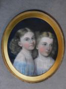 An oval framed pastel portrait of two young girls posing together, unsigned. 65x57cm