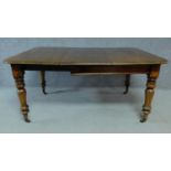 A Victorian mahogany extending table on turned tapering supports terminating on brass cup casters.