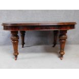 A Victorian figured mahogany extending dining table on turned tapering fluted supports terminating