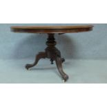 A Victorian mahogany circular dining table with tilt top action raised on carved tripod supports.