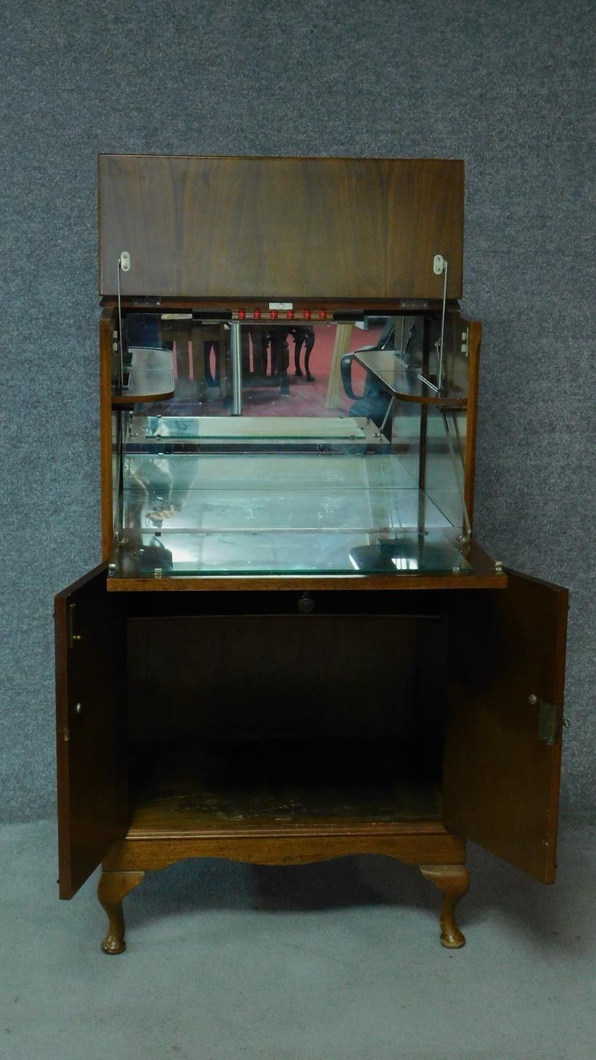 A Georgian style figured walnut cocktail cabinet fitted with mirrored interior raised on cabriole