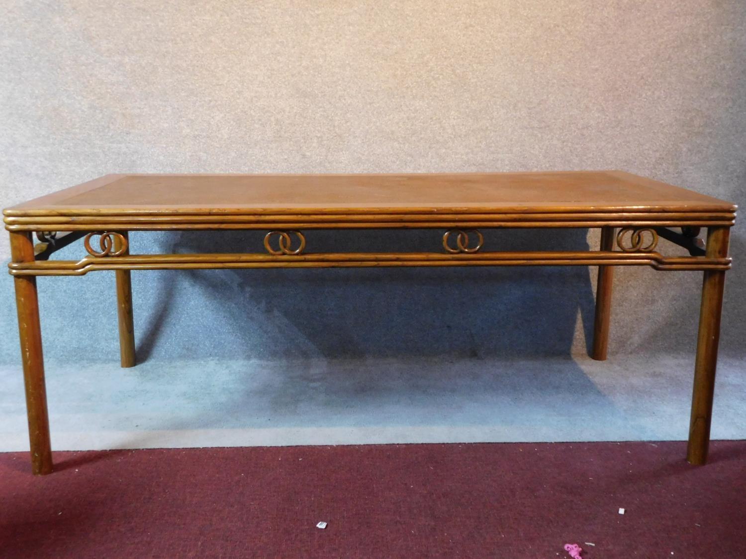 A Chinese hardwood rattan topped dining table raised on circular section supports. Possibly retailed