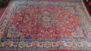 A large Persian Tabriz style rug with central double pendant medallion on a rouge field framed