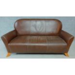 A shaped back two seater sofa in tan leather upholstery on swept supports. H.87 W.170 D.77cm
