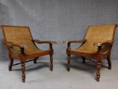 A pair of Colonial teak framed reclining planter's chairs with foldout foot rests on turned tapering