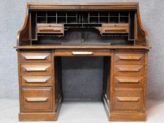 A late 19th century oak roll top desk with tambour shutter enclosing fitted interior above an