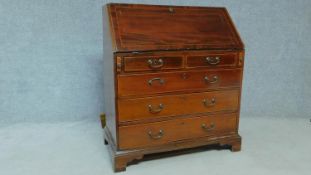 An Edwardian mahogany bureau with fitted compartment above two short over three long drawers on