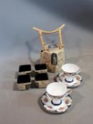 A ceramic Malaysian tea set and a pair of porcelain tea cups and saucers. The tea cups have a