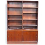 A mid 20th century rosewood open library bookcase with sliding doors to base cupboards, raised on