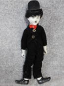 A vintage porcelain Charlie Chaplain doll. Depicting the Little Tramp with a painted porcelain head,