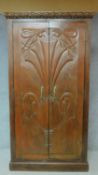 An Art Nouveau style chestnut wardrobe with shell carved panel doors enclosing shelved interior. H.