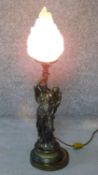 An gilded brass table lamp of an elegant lady leaning against a torch. There is a putti looking over