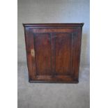 A Georgian oak hanging corner cupboard fitted with panel door. H.97 x 87cm