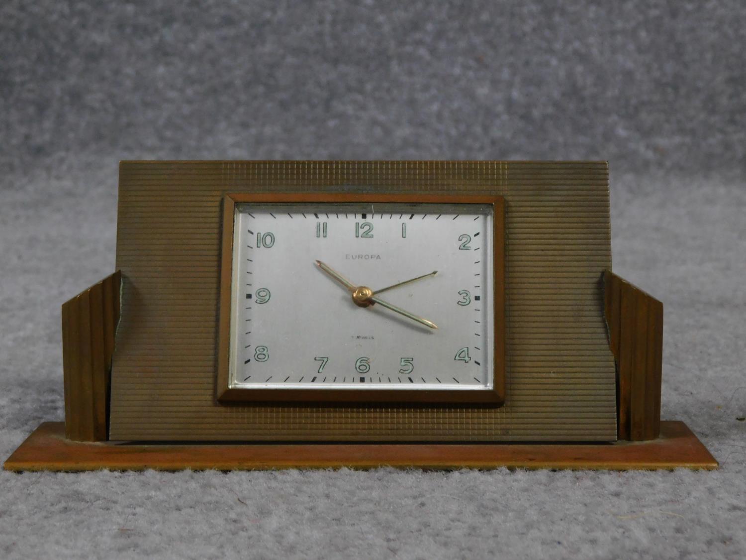 An Art Deco brass desk clock by Europa. Luminous numbers. Geometric form with linear detailing. H.