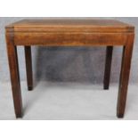 A mid 20th century oak fold over top table with interior compartment, raised on square supports. H.